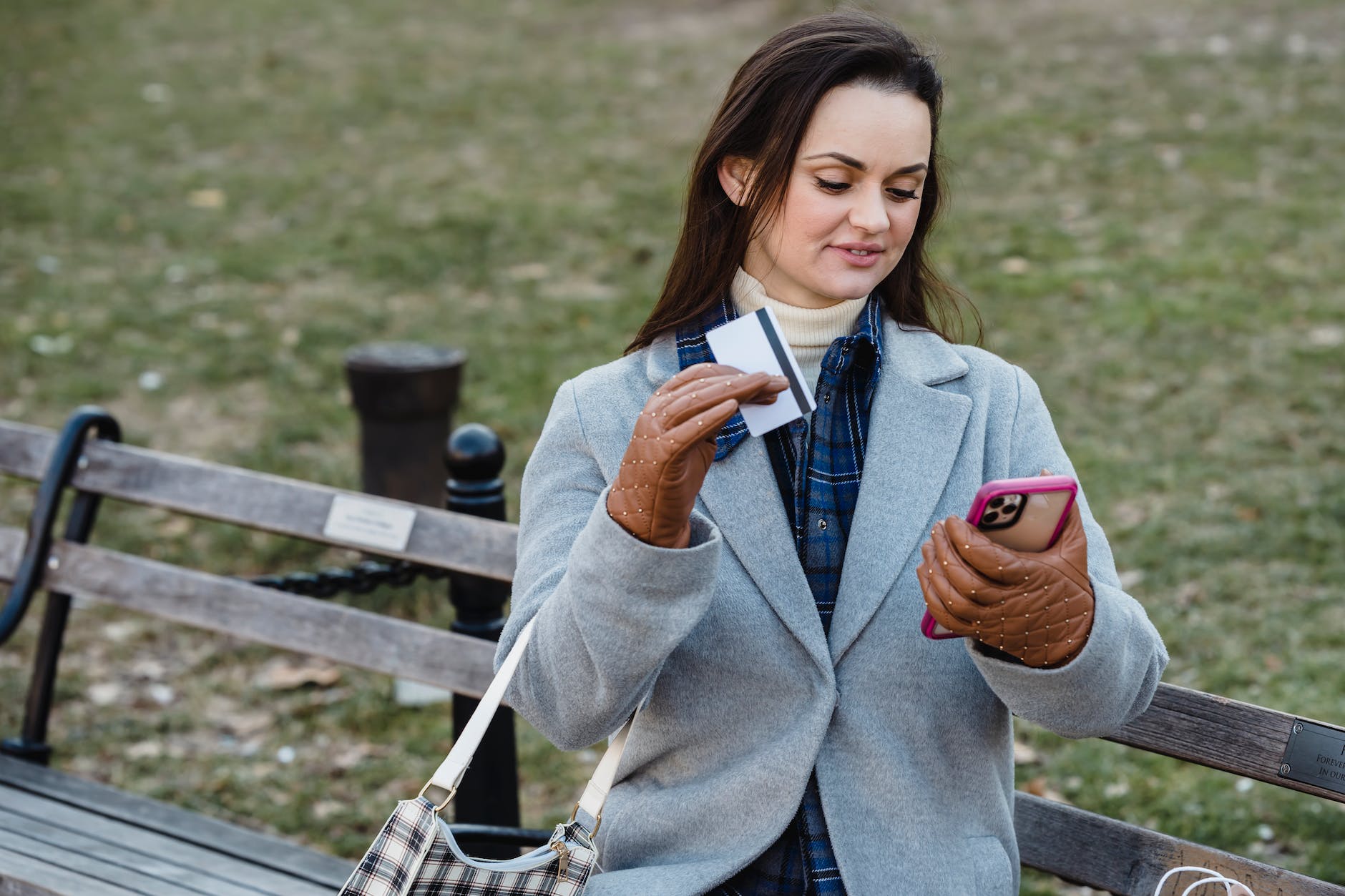 glad woman making online payment via smartphone in spring park